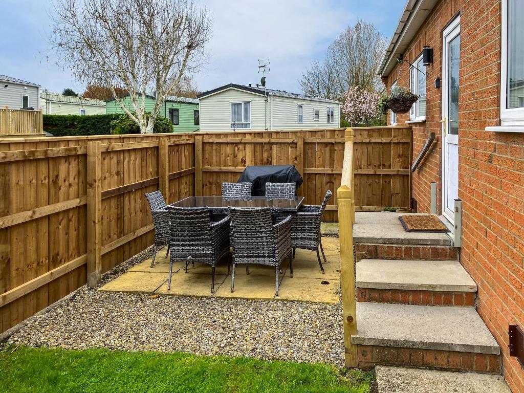 een terras met een tafel, stoelen en een hek bij Swaleside Cottage in Topcliffe