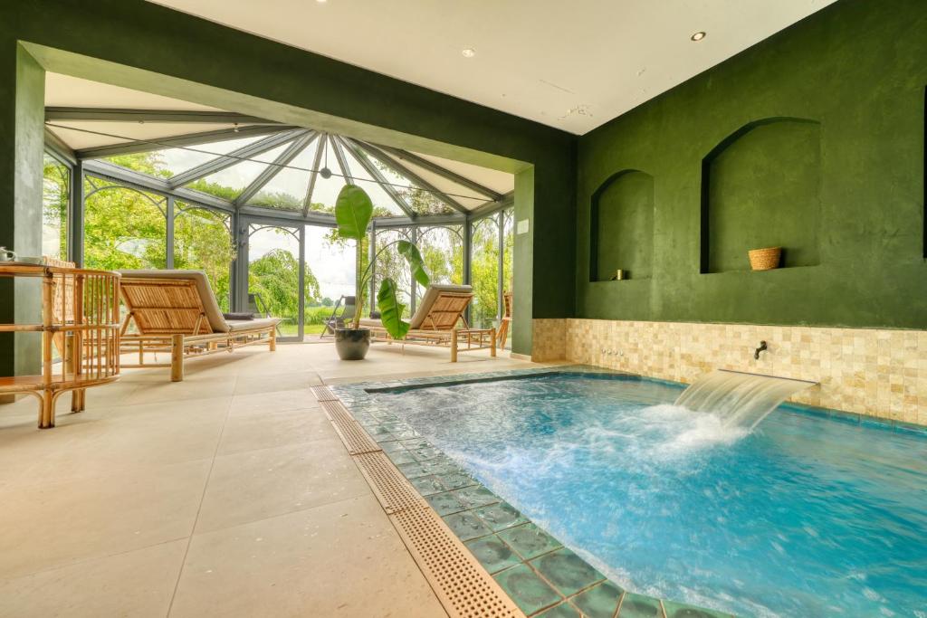 an indoor pool in a house with green walls at Domaine de Bellevue - Restaurant & Spa in Neufmoutiers-en-Brie