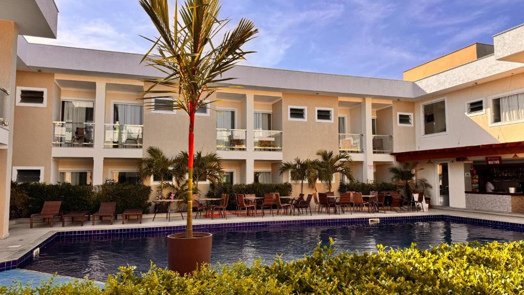 a hotel with a palm tree in front of a swimming pool at Orquídeas Praia Hotel in Porto Seguro