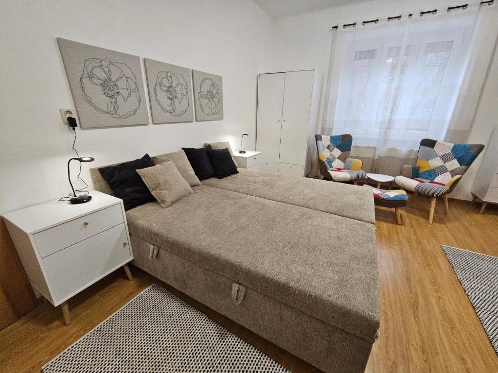 ein Schlafzimmer mit einem großen Bett und einem Stuhl in der Unterkunft Harmonia Budget apartman in Dunajská Streda