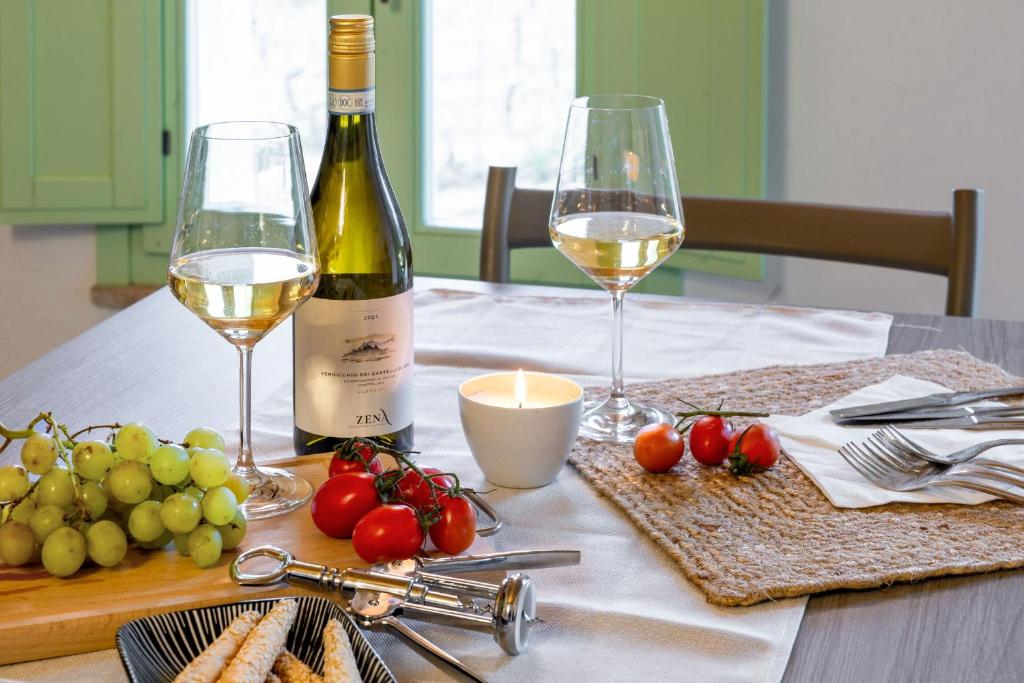 een tafel met twee glazen witte wijn en druiven bij Italian Experience-Zena Suite in San Paolo di Iesi