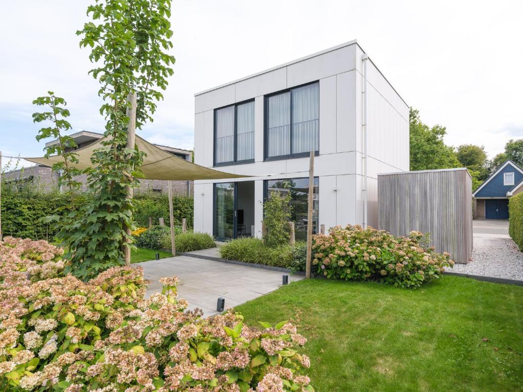 a white house with a garden at Kubus Nr. 228 | 4 Pers. in Zeewolde
