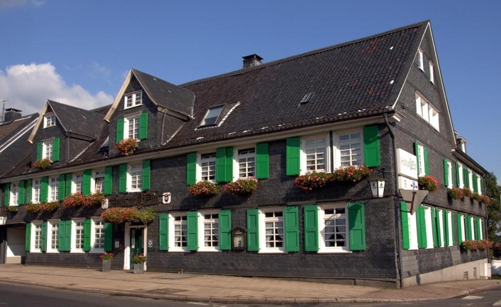 ein schwarzes und grünes Gebäude mit grünen Rollläden in der Unterkunft Hotel Zur Eich in Wermelskirchen