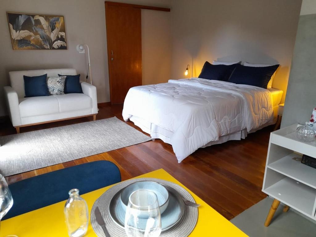 een slaapkamer met een bed, een bank en een tafel bij Chalé Topázio Gonçalves in Gonçalves