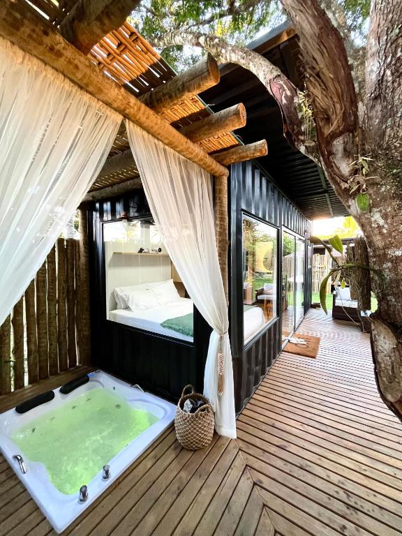 a hot tub on a deck with a tree at Villa Manah in Itaúnas