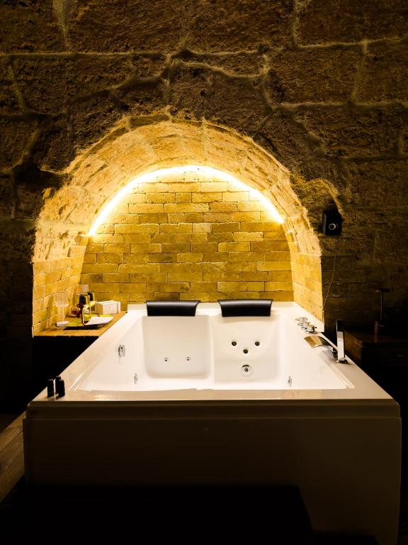 a large bath tub in a brick walled bathroom at Corte Lirice Paradiso in Gioia del Colle