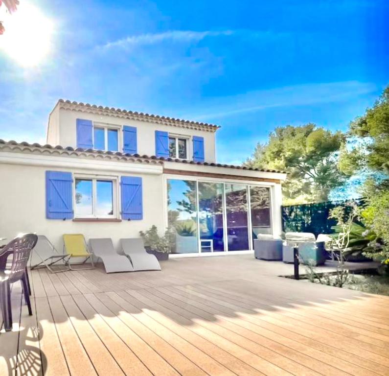 une maison dotée d'une terrasse en bois avec des chaises. dans l'établissement Villa moderne vue mer et collines aux Portes des Calanques, à La Ciotat
