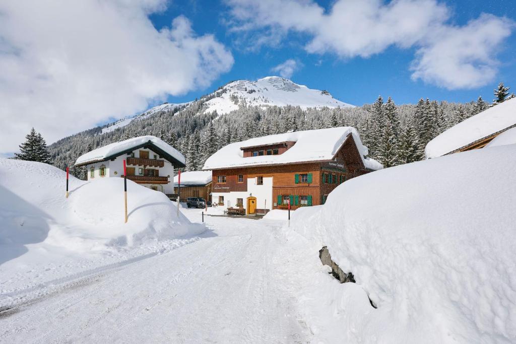 a snow covered house with a mountain in the background at Appartement Omesberg 1 in Lech am Arlberg