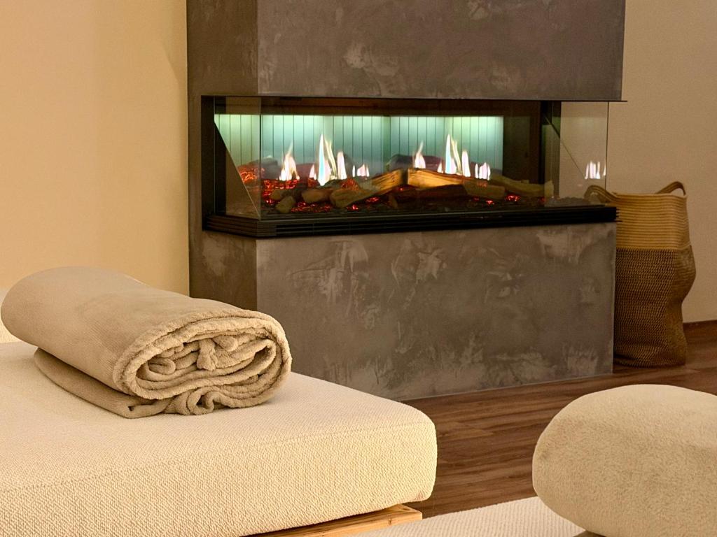 a fireplace in a living room with a towel on a bed at Residence Hotel Alpinum in Campo Tures