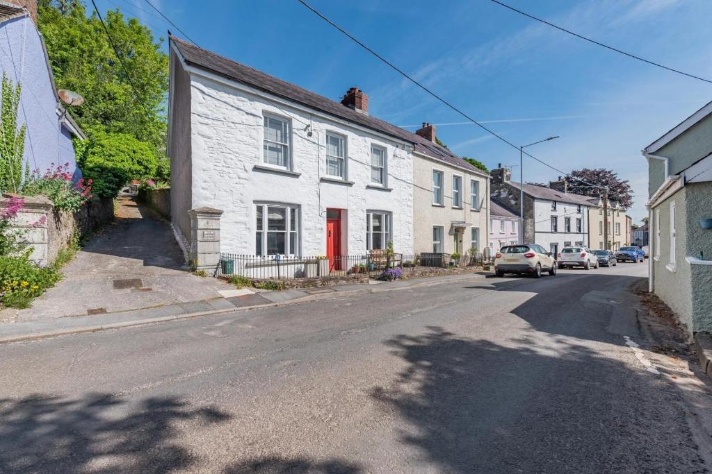 a white house with a red door on a street at 3 Bed in Llansteffan oc-78278 in Llanstephan