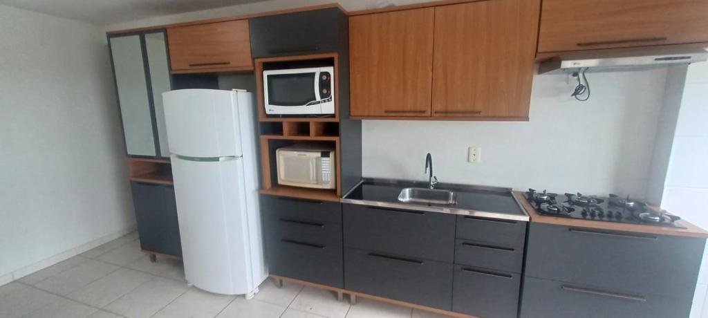 eine Küche mit Kühlschrank und Mikrowelle in der Unterkunft Apartamento mobiliado próximo Unesc em Criciúma in Criciúma