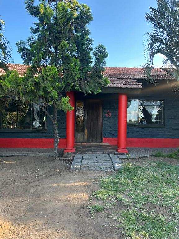 una casa con colonne rosse e un albero di fronte di Protea Guesthouse a Phalaborwa