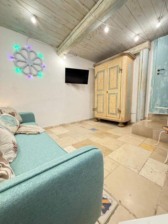 een woonkamer met een blauwe bank en een tv bij B&B Casa Fiore in Polignano a Mare