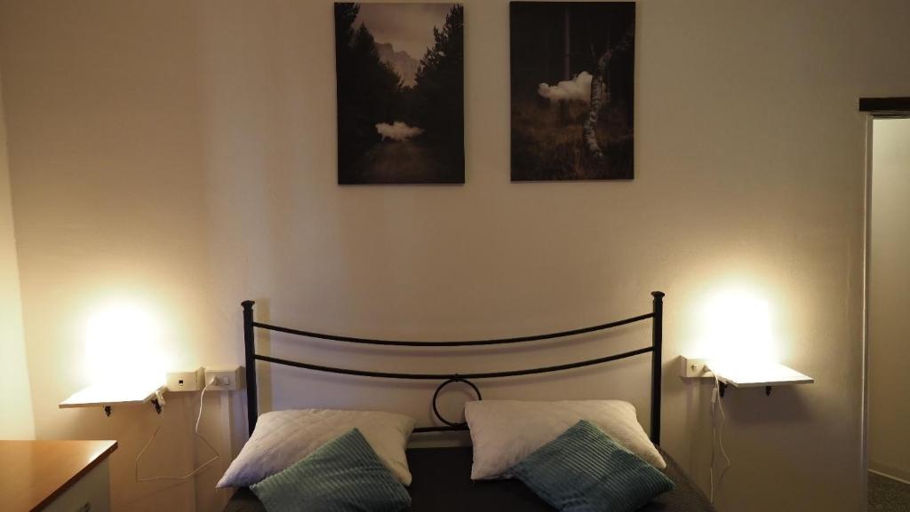 een slaapkamer met een bed met twee lampjes aan de muur bij Casa Vacanza Bettega in Pianosinatico