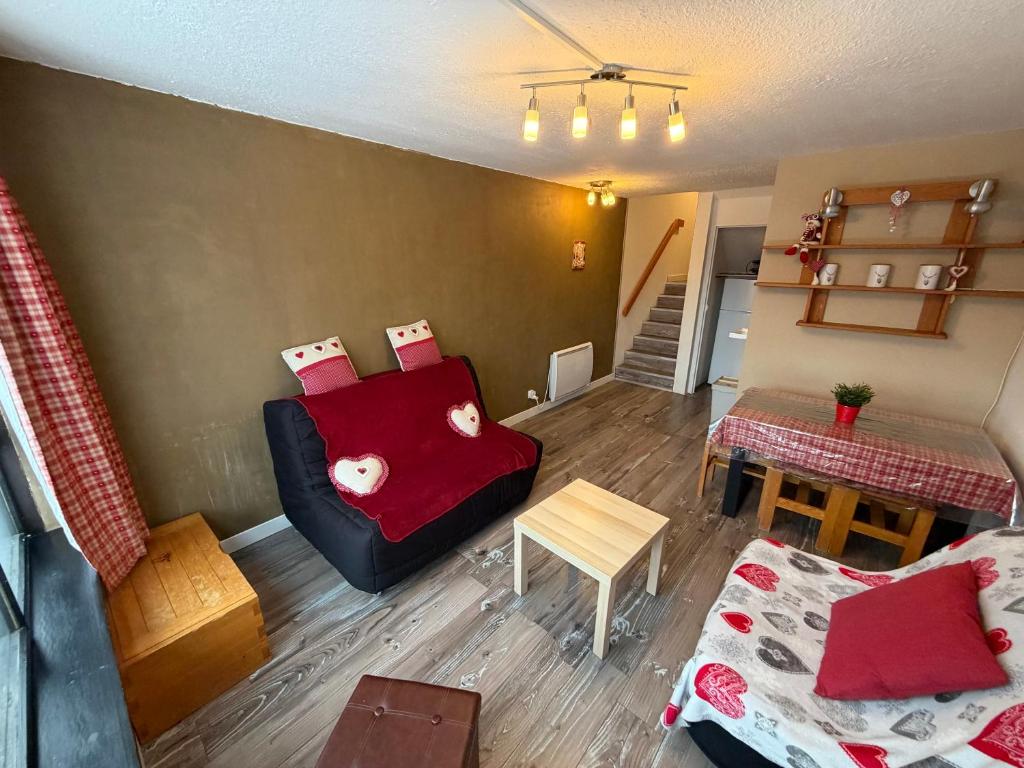 Appartement Résidence Cortina3 في بوي-سانت-فينسينت: غرفة معيشة مع أريكة حمراء وطاولة