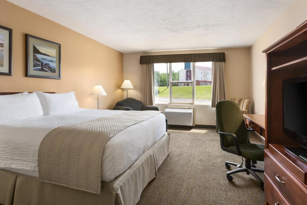 ein Hotelzimmer mit einem Bett und einem TV in der Unterkunft Days Inn & Suites by Wyndham Moncton in Moncton
