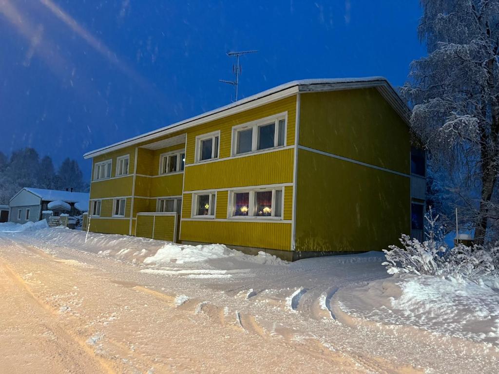 a yellow house on a snow covered road at Loft house Karihaara in Kemi