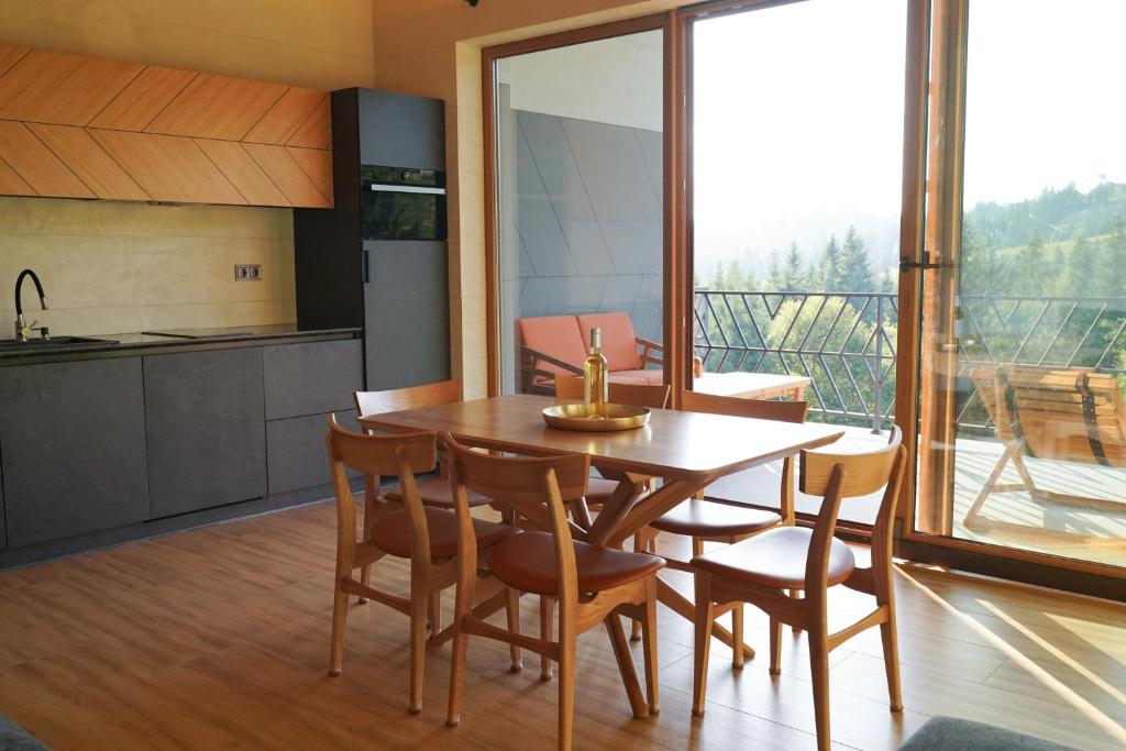 a kitchen and dining room with a wooden table and chairs at Тхаті in Yablunytsya