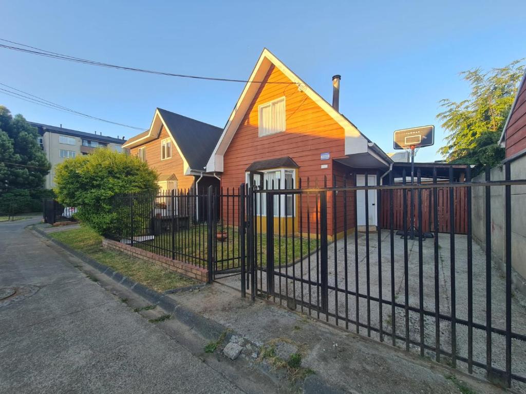 a house behind a fence with a basketball hoop at Reina Sofia II in Valdivia