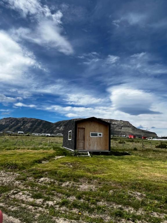 une petite cabane dans un champ sous un ciel nuageux dans l'établissement Tiny House Camino 3, à Puerto Natales