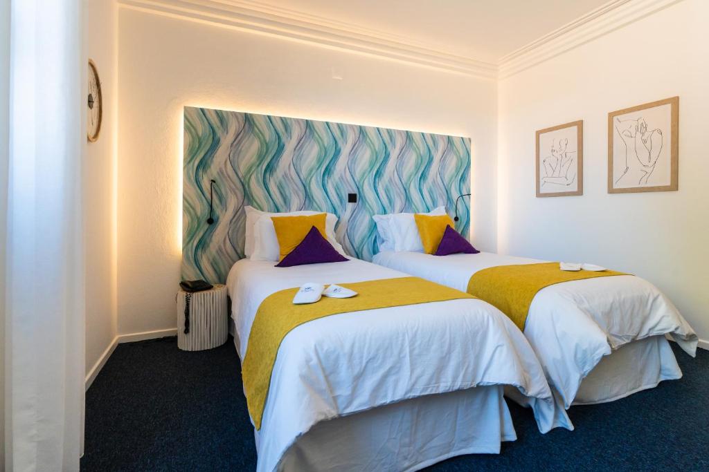 Cette chambre d'hôtel comprend 2 lits jaunes et bleus. dans l'établissement Mediterrâneo Madeira, à São Vicente
