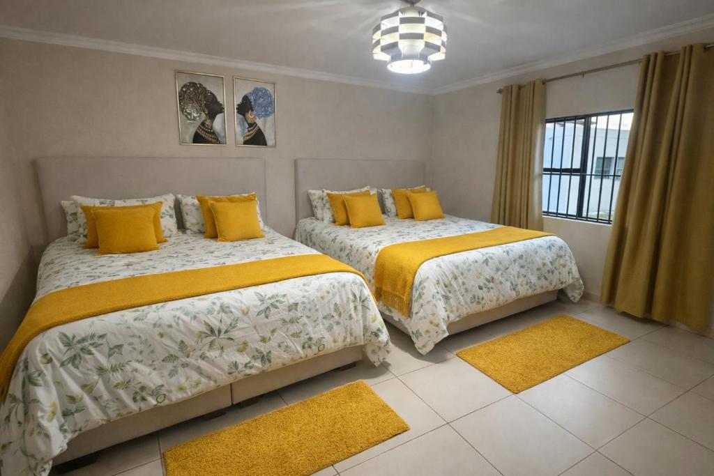 - 2 lits dans une chambre avec des oreillers jaunes dans l'établissement VinVid Harties Guest House, à Hartbeespoort