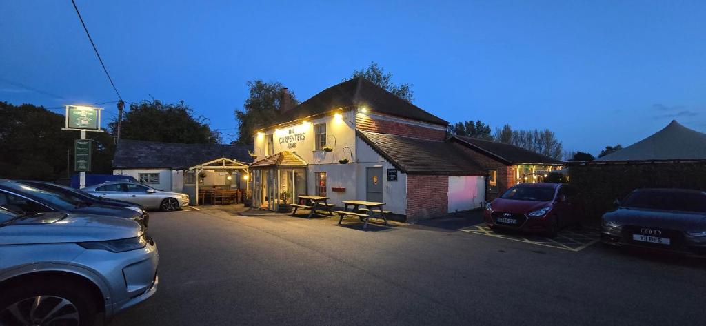 una casa con luces encendidas en un estacionamiento en The Carpenters Arms, en Newbury