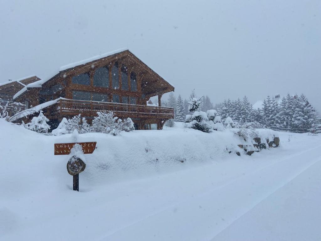 una cabaña cubierta de nieve con un cartel delante en Chalet Serre Chevalier, en Le Monêtier-les-Bains