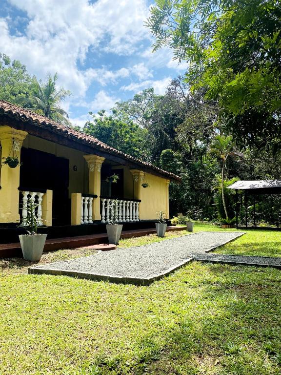 a yellow house with a porch and a yard at Villa Meleno in Weligama
