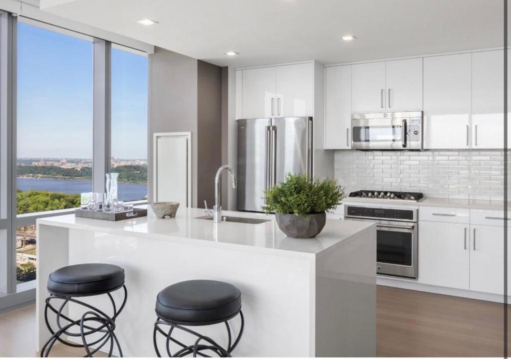 eine Küche mit weißen Schränken und einer Theke mit Stühlen in der Unterkunft Everlasting Reality in Fort Lee