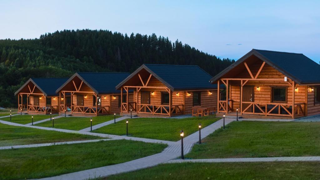 a log cabin with lights on the grass at Domki Sudecka Przystań in Duszniki Zdrój