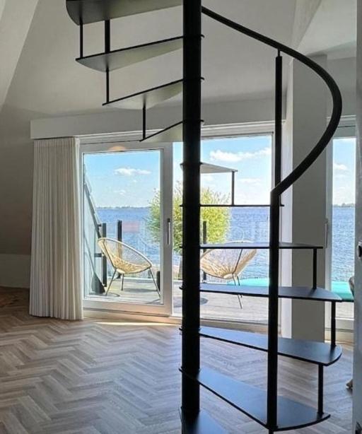 a living room with a spiral staircase and a large window at Lake House 10 - 4 Person Lake view apartment! in Offingawier