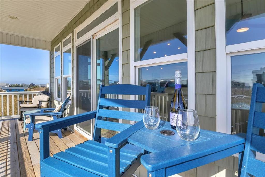 een blauwe bank op een veranda met wijnglazen bij Sunsets and the Sea in Thomas Landing