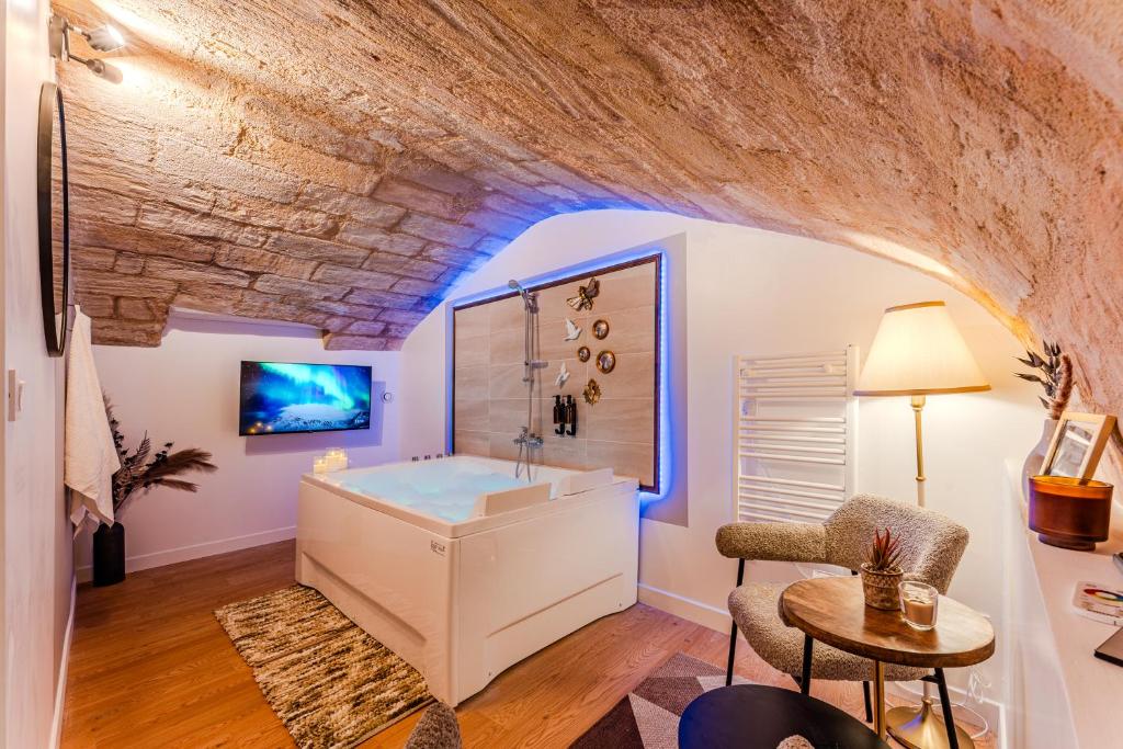 a bathroom with a tub in a room with a stone wall at Suite d'Exception sous Voûtes avec Spa & Cinéma in Bordeaux