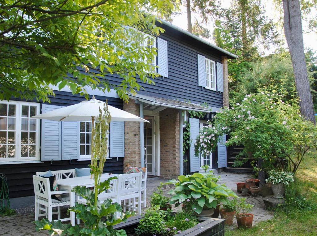 a blue house with white chairs and an umbrella at Villa Hjortekær in Kongens Lyngby