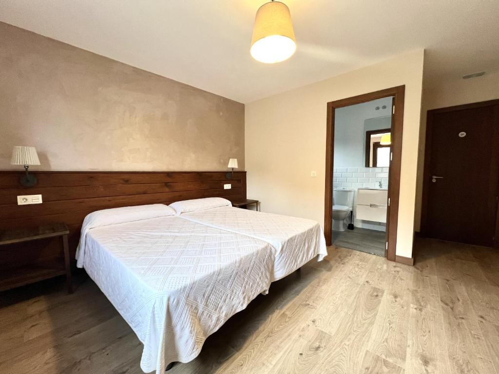 een slaapkamer met een wit bed en een badkamer bij La Casona de Omaña in Fasgar
