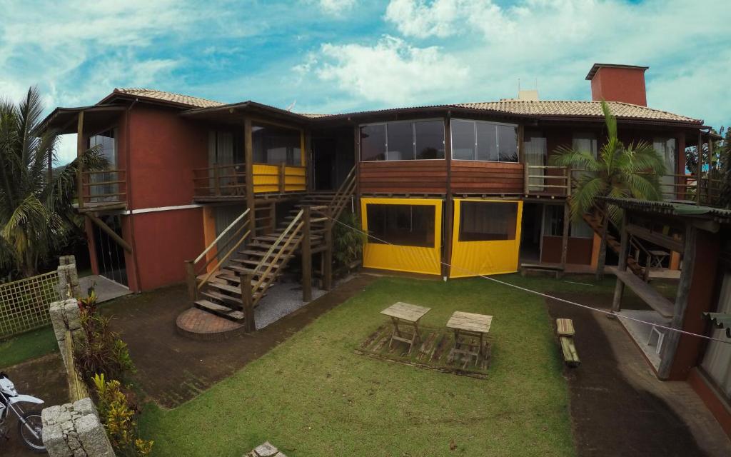 uma casa com uma porta amarela e um quintal em Condominio Aldeia da Praia em Garopaba