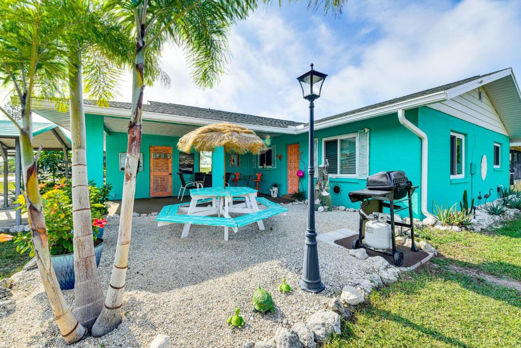 a blue house with a picnic table and palm trees at Pet-Friendly Bradenton Home 1.5 Mi to Cortez Beach in Bradenton