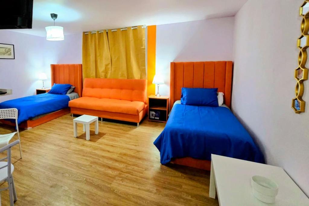 a bedroom with two beds and an orange chair at Suite Naranja moderna para 3 huéspedes Cocina equipada, Wi-Fi rápido y excelente ubicación céntrica in Mexico City