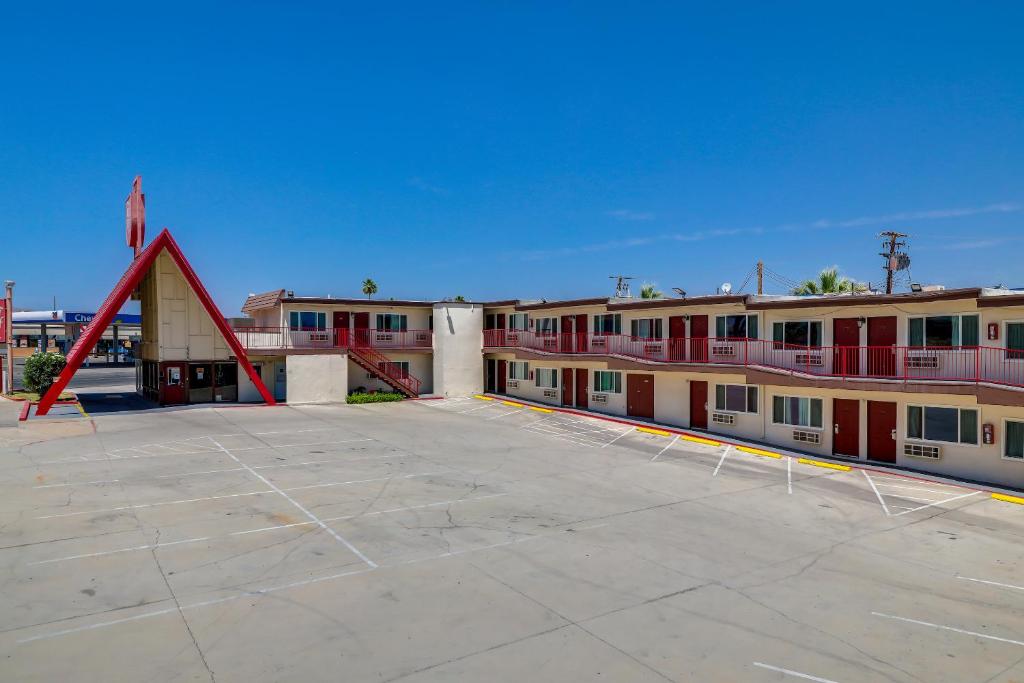 a building with a red triangle in a parking lot at Red Roof Inn Needles in Needles