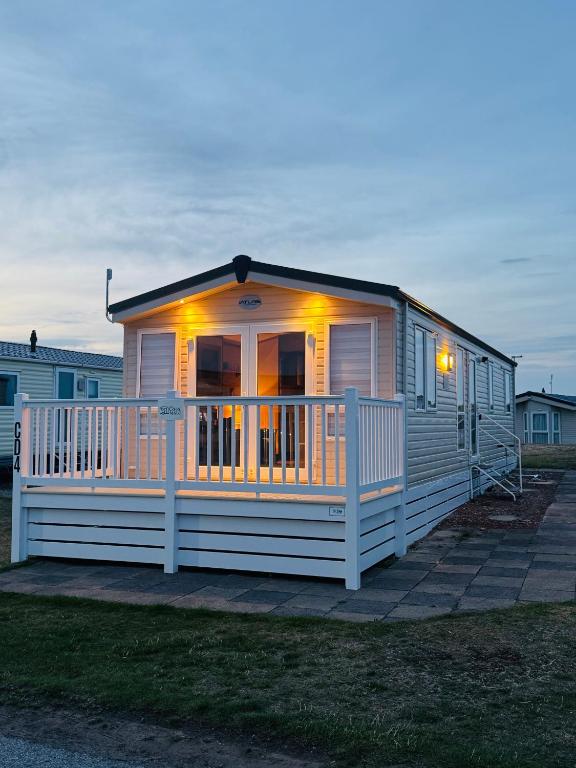 a white house with a porch with lights on it at Casa MALC Caravan in Lossiemouth