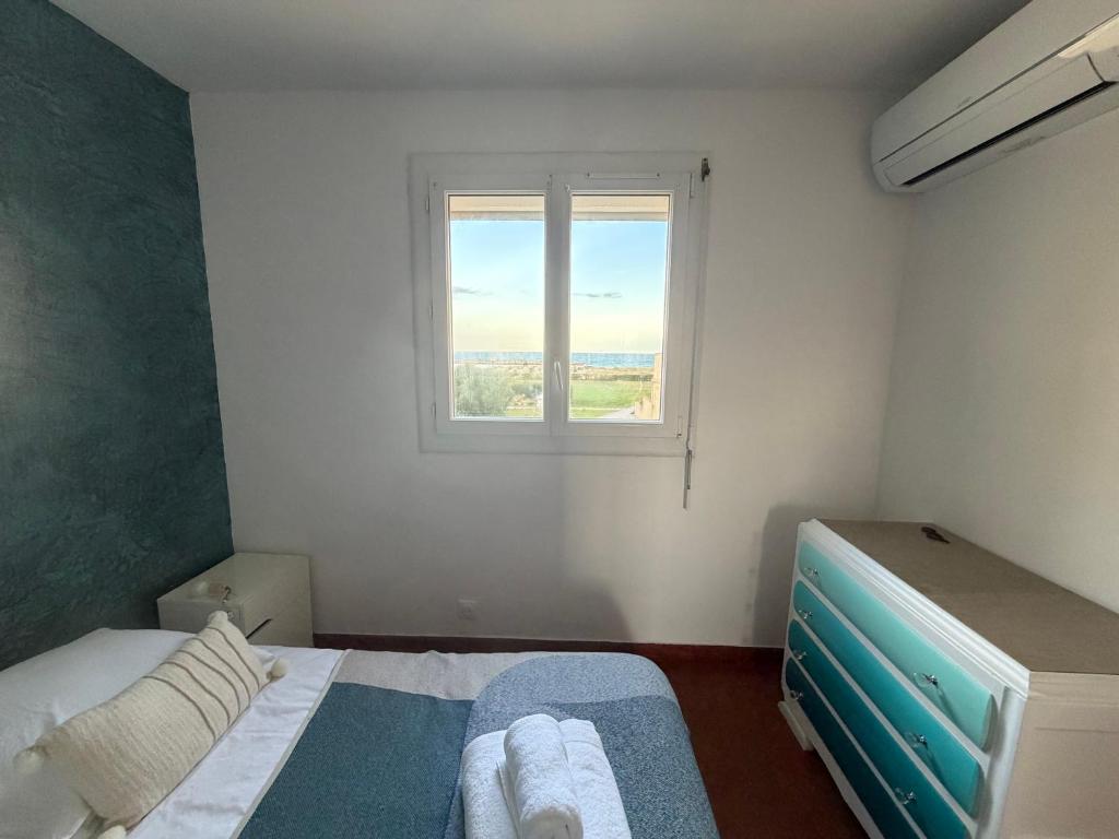 ein kleines Schlafzimmer mit einem Bett und einem Fenster in der Unterkunft Comfortable apartment with sea view in Le Barcarès