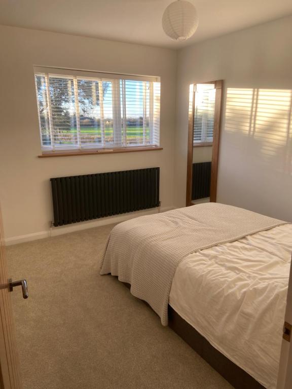 a bedroom with a bed and two windows at Comfortable Homestay by Earith Lakes in Earith