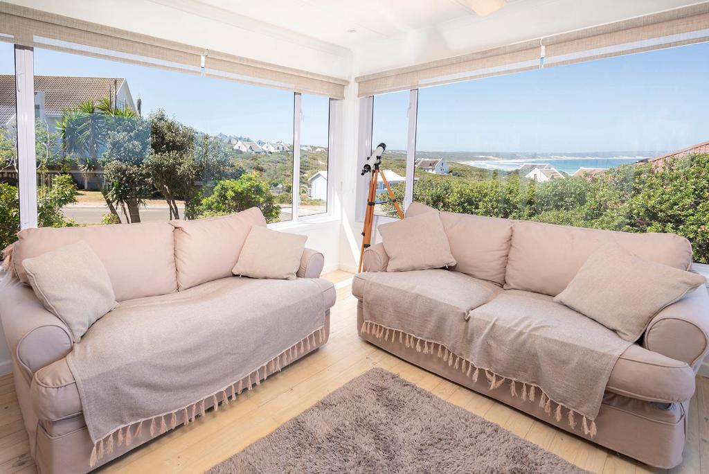 a living room with two couches and a large window at Leef op Hoop in Boggomsbaai