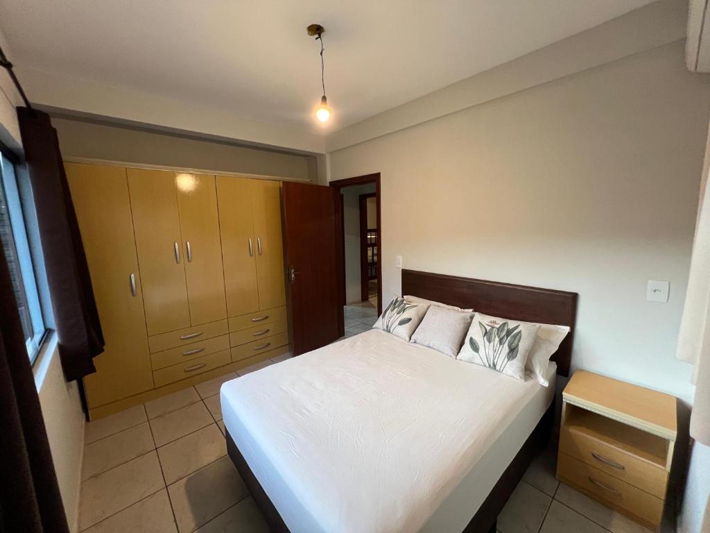 een slaapkamer met een bed met witte lakens en kussens bij Casa Brisa do Siriú in Garopaba