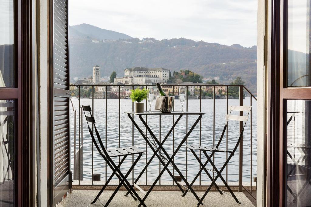 een tafel en stoelen op een balkon met uitzicht op het water bij Orta Paradise 26 in Orta San Giulio