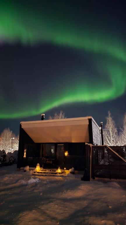 a building with the aurora in the sky at Arctic Circle Aurora Guesthouse in Rovaniemi
