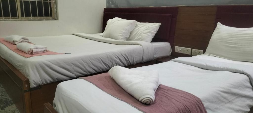 Tres camas con sábanas blancas y un juguete para perros sobre ellas. en MeDa-Frin's Hotel, en Chennai