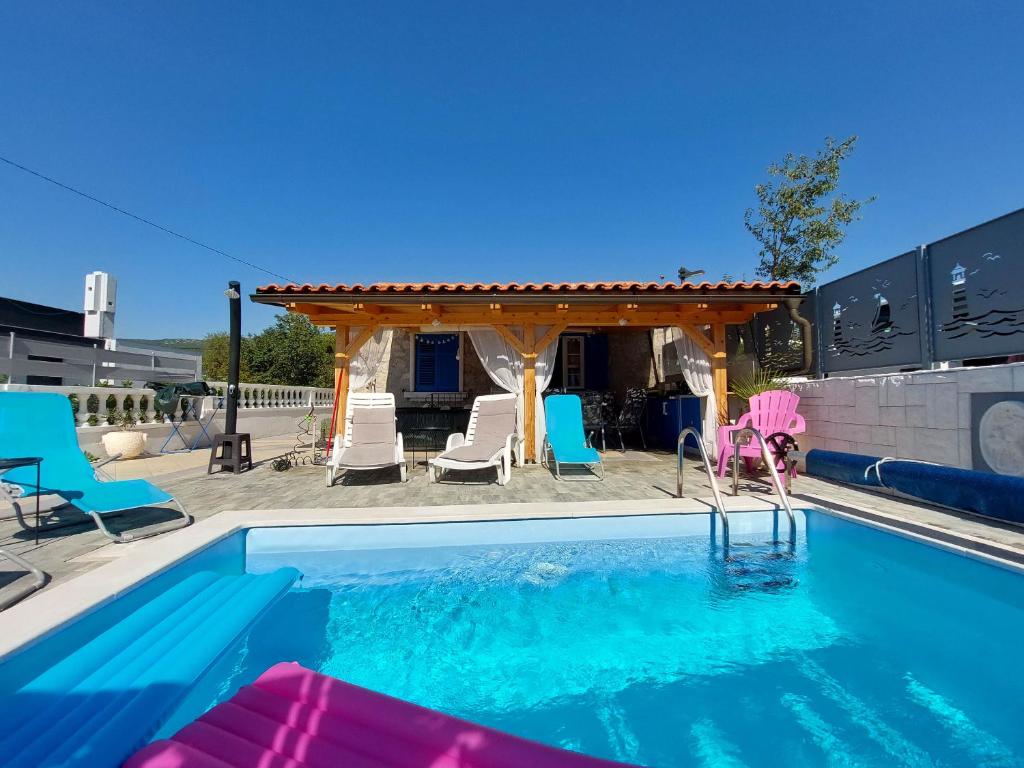 a swimming pool with chairs and a gazebo at House House Jadranovo in Jadranovo
