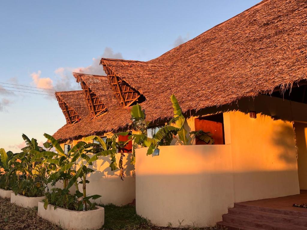 een huis met een rieten dak en wat planten bij Villa Papaya in Jomba